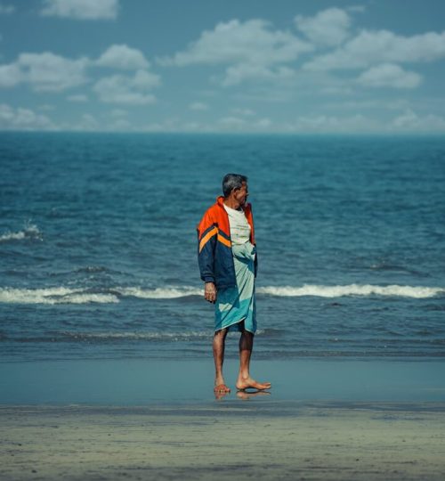 a man standing on a beach next to the ocean